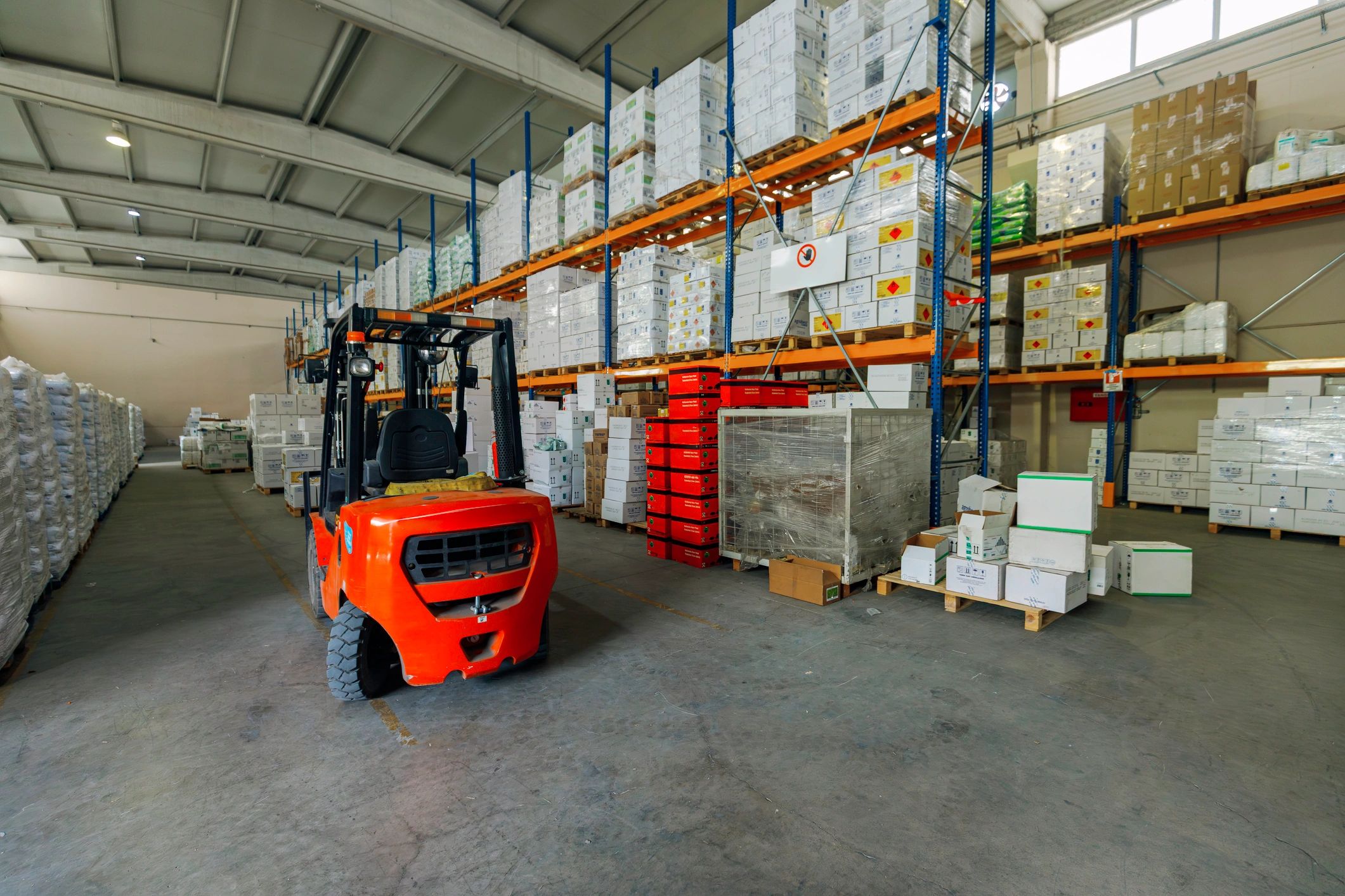 Warehouse aisle with stacked goods and pallets